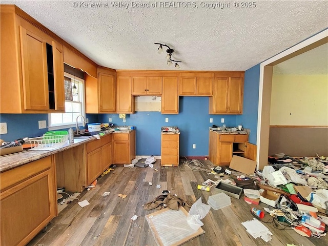 kitchen with brown cabinets, wood finished floors, and a textured ceiling