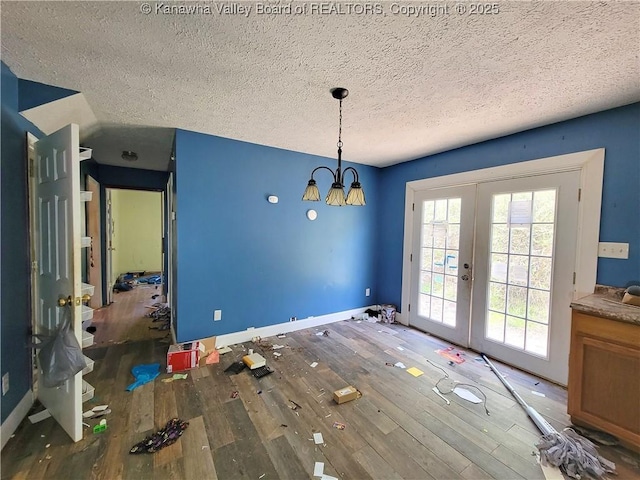 unfurnished dining area featuring plenty of natural light, french doors, wood finished floors, and a textured ceiling