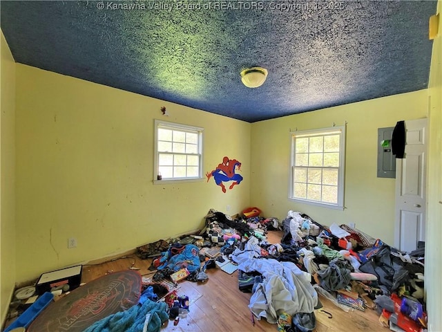 unfurnished bedroom featuring hardwood / wood-style flooring, a textured ceiling, and multiple windows