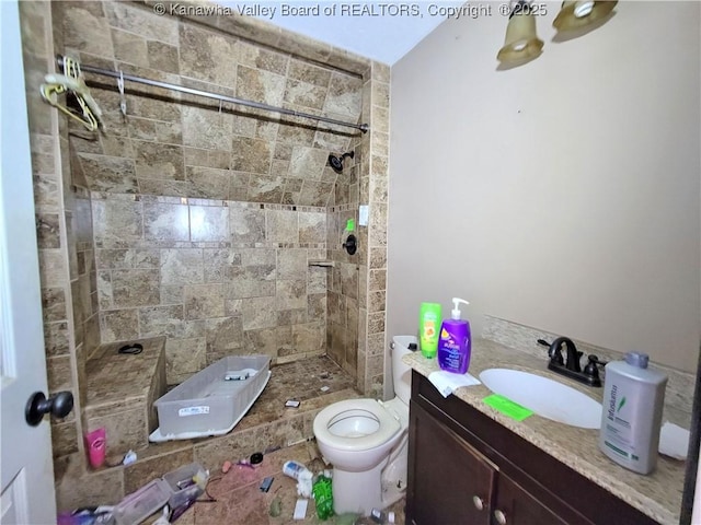 bathroom with vanity, toilet, and tiled shower