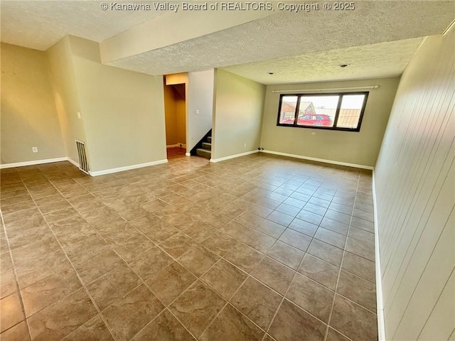 spare room with stairway, tile patterned floors, visible vents, baseboards, and a textured ceiling
