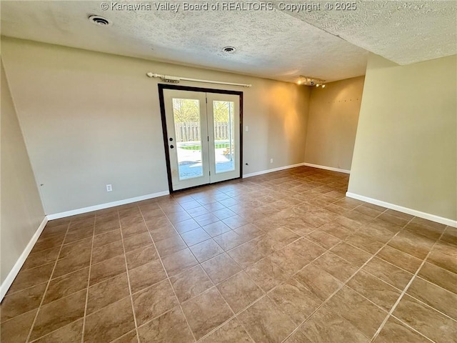 tiled spare room with baseboards, french doors, a textured ceiling, and visible vents