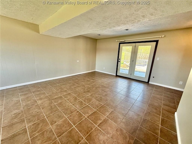 spare room with dark tile patterned floors, a textured ceiling, baseboards, and french doors