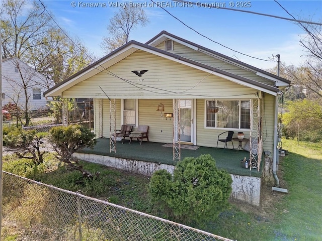 rear view of house featuring fence, a yard, and covered porch