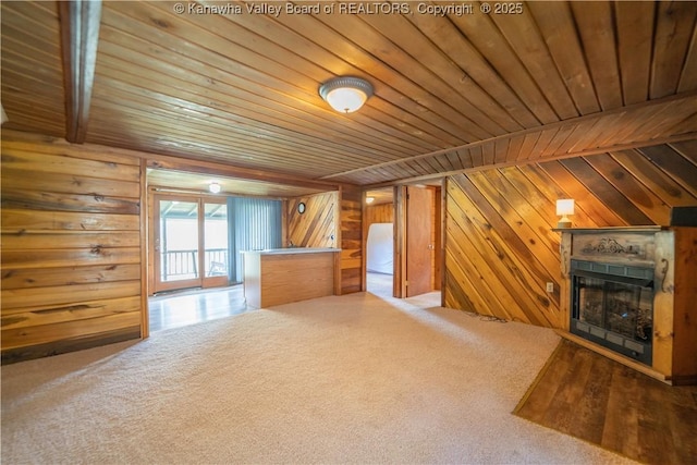 additional living space featuring a fireplace, wooden walls, carpet, and wood ceiling