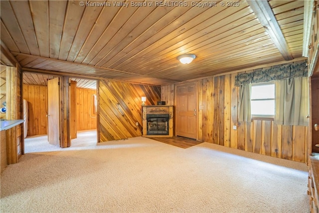 unfurnished living room featuring a fireplace, carpet flooring, wooden ceiling, and wood walls