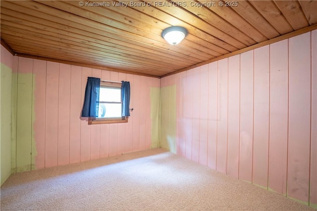 empty room with wood ceiling, wood walls, and carpet