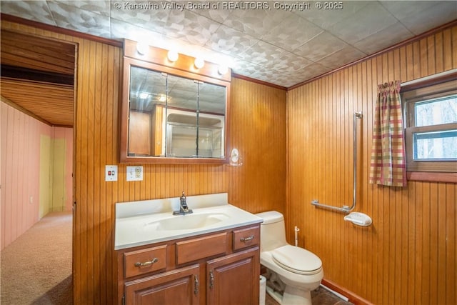 bathroom featuring ornamental molding, toilet, wood walls, and vanity