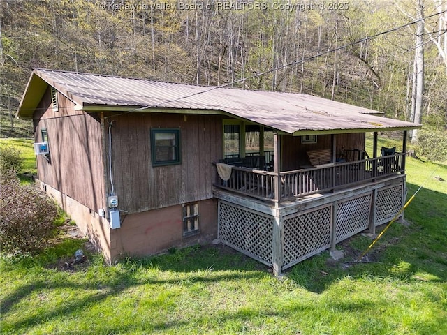 back of house featuring a lawn, a wooded view, and metal roof