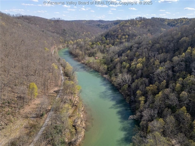 aerial view featuring a water and mountain view and a wooded view