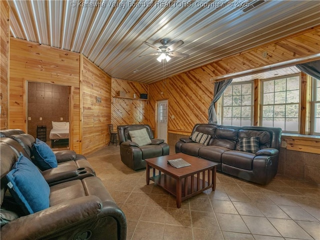 living area with ceiling fan, wood walls, and tile patterned floors