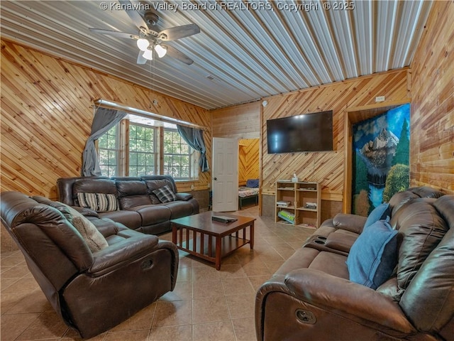 living room featuring wood walls, ceiling fan, and tile patterned floors
