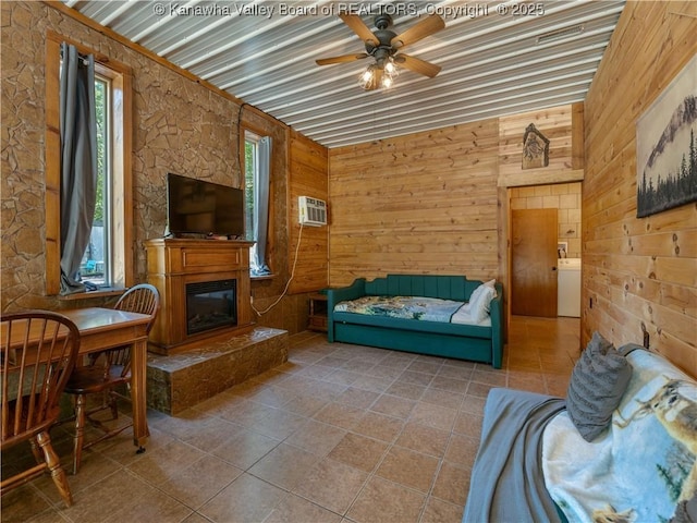 living room with a glass covered fireplace, wooden walls, a wealth of natural light, and a ceiling fan