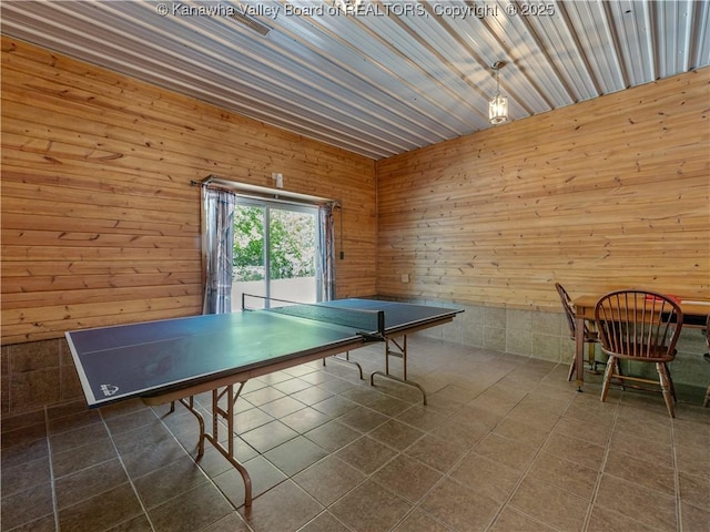 recreation room with tile patterned flooring and wooden walls