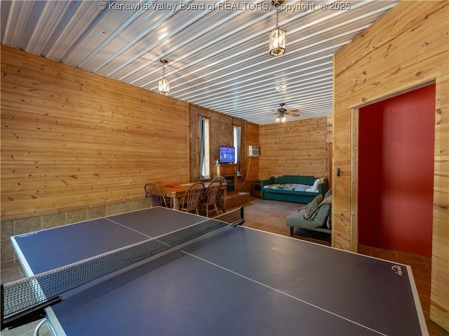 recreation room with ceiling fan and wooden walls