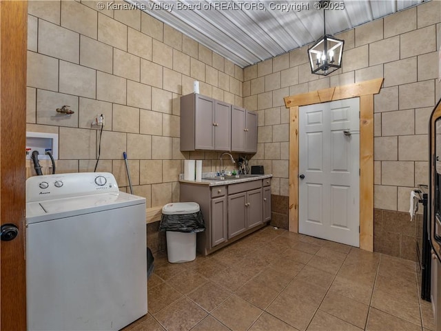 laundry area featuring tile walls, dark tile patterned flooring, cabinet space, and washer / dryer