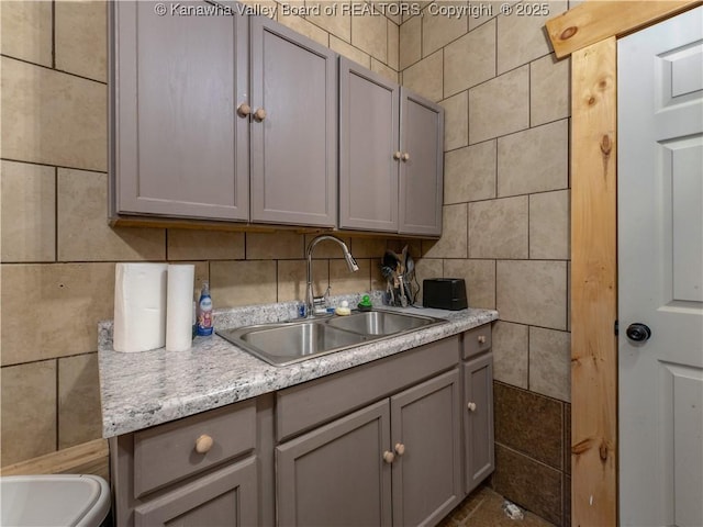 kitchen featuring light countertops, tile walls, gray cabinets, and a sink