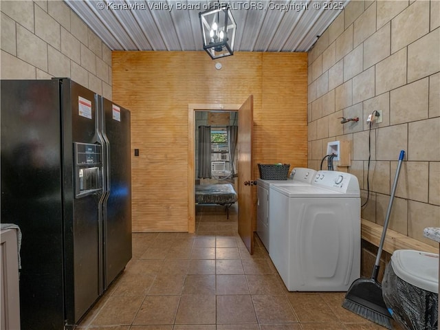 clothes washing area featuring separate washer and dryer, tile patterned floors, and tile walls