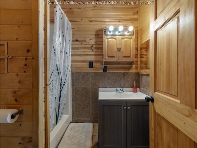 full bathroom featuring wood walls and vanity