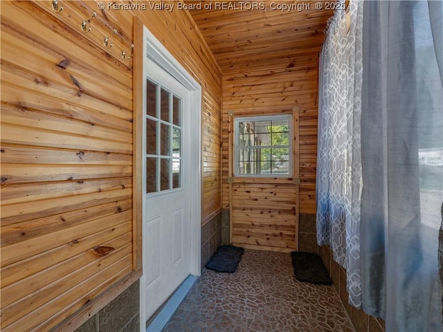 doorway with wooden ceiling and wood walls