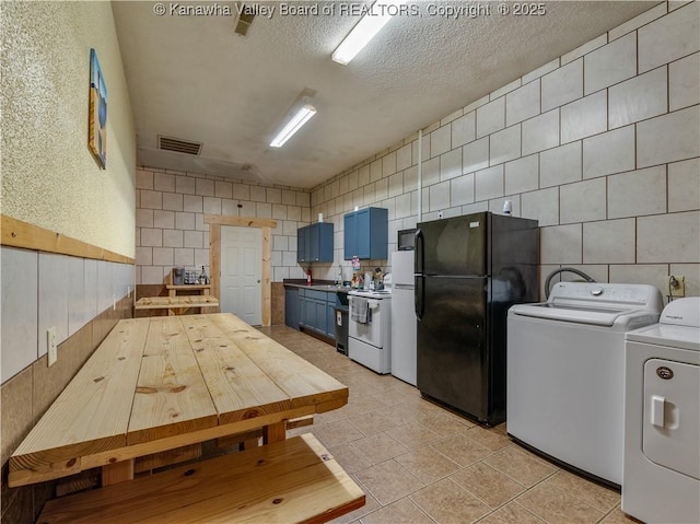 kitchen with washer and clothes dryer, tile walls, visible vents, white appliances, and blue cabinetry