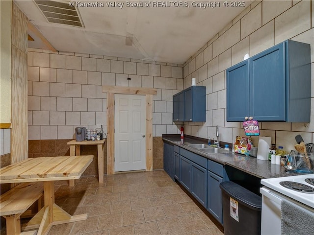 kitchen featuring a sink, tile walls, dark countertops, visible vents, and blue cabinetry