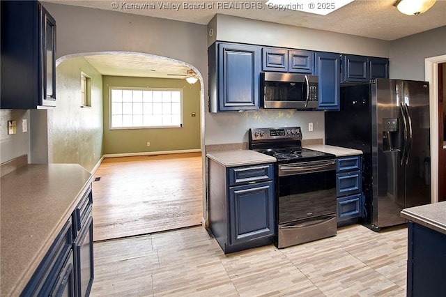 455 Kane St, Milton, WV 25541 - kitchen featuring black refrigerator with ice dispenser, arched walkways, electric range oven, stainless steel microwave, and blue cabinetry