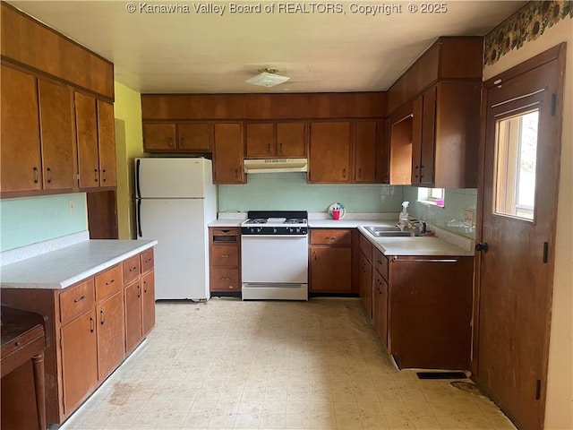 kitchen featuring light floors, backsplash, under cabinet range hood, and white appliances