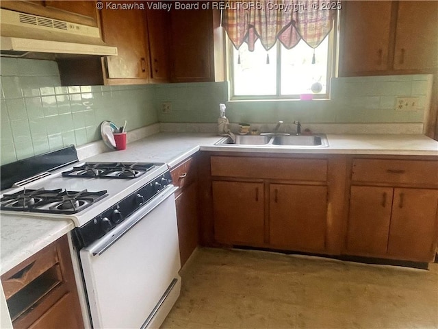 kitchen featuring under cabinet range hood, a sink, white gas range oven, and light countertops