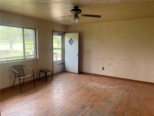spare room with baseboards, wood finished floors, and ceiling fan