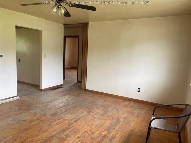 spare room featuring hardwood / wood-style flooring, baseboards, a ceiling fan, and visible vents