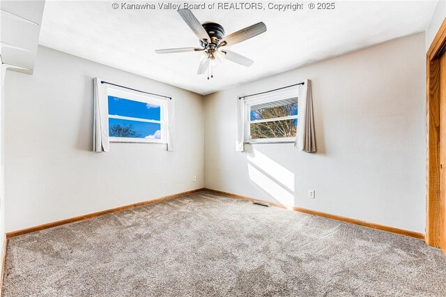 carpeted spare room with a ceiling fan and baseboards