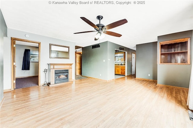 unfurnished living room with wood finished floors, visible vents, a ceiling fan, and baseboards