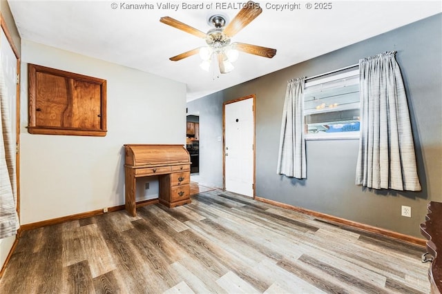 unfurnished room featuring baseboards, wood finished floors, and ceiling fan