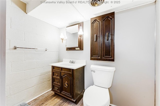 bathroom with baseboards, wood finished floors, toilet, and vanity