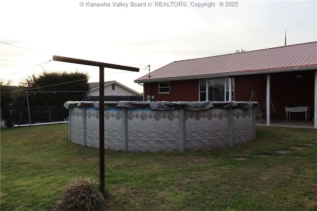 view of pool featuring a lawn, a covered pool, and fence