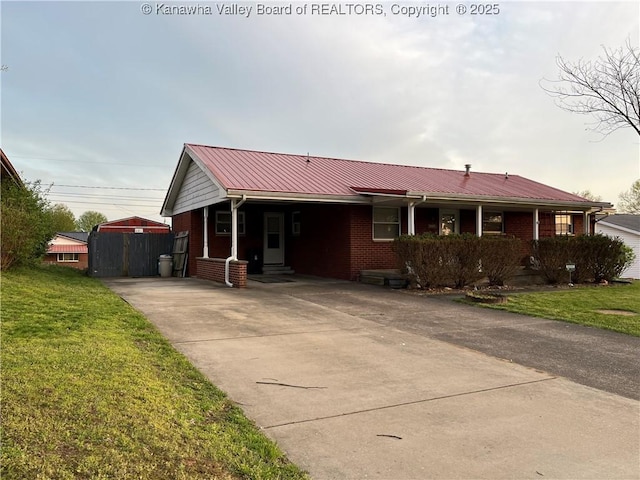 ranch-style home featuring brick siding, driveway, a front lawn, and metal roof