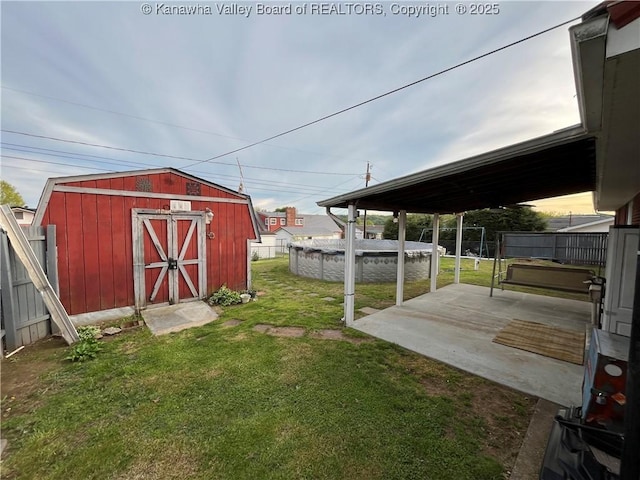 view of yard with a fenced backyard, an outdoor structure, a patio, and a storage unit