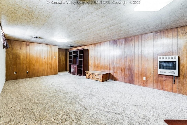 empty room with carpet flooring, heating unit, and wooden walls