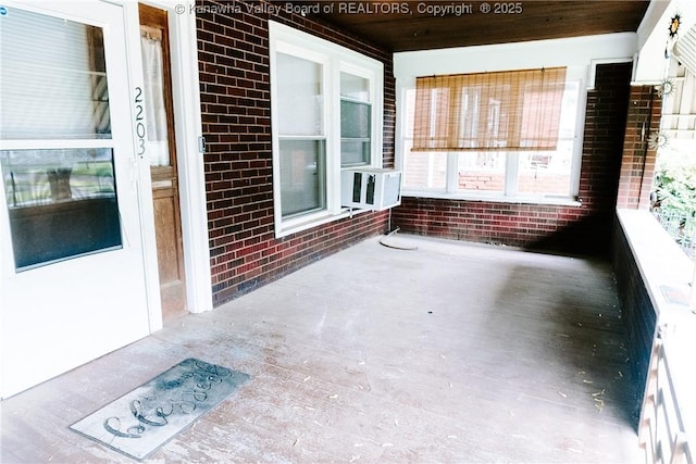 unfurnished sunroom featuring wooden ceiling, cooling unit, and brick wall