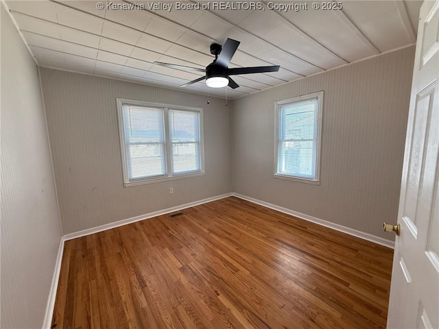 empty room with visible vents, ceiling fan, wood finished floors, and baseboards