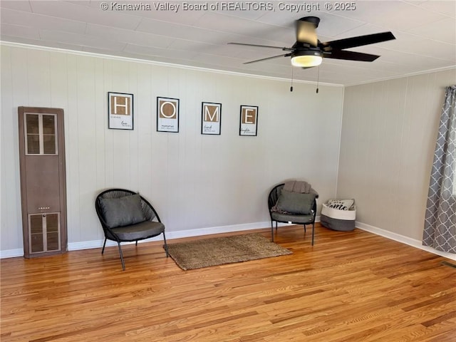 living area featuring a heating unit, light wood-style floors, ceiling fan, crown molding, and visible vents