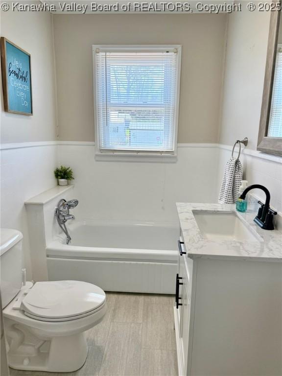 full bathroom with toilet, a bath, and vanity