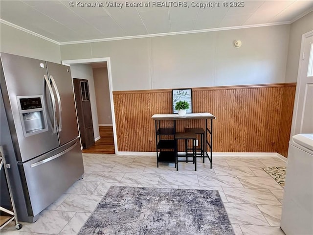 kitchen featuring wainscoting, stainless steel refrigerator with ice dispenser, crown molding, and marble finish floor