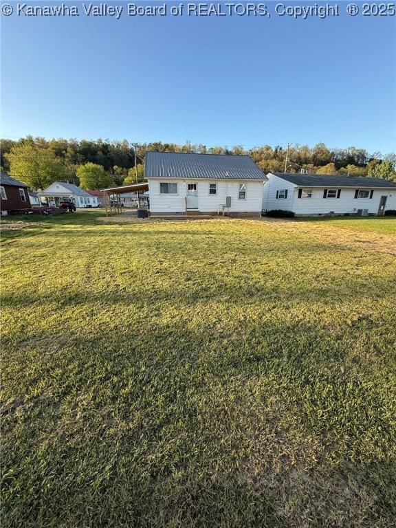 rear view of property featuring metal roof, a carport, and a yard