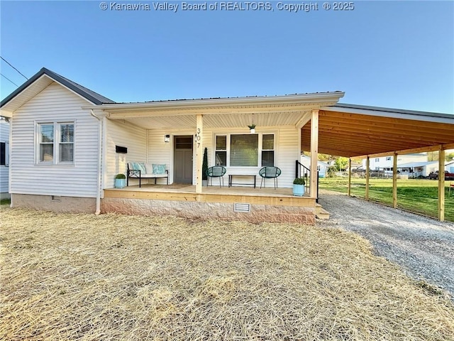 view of front of property featuring driveway, metal roof, a porch, and crawl space