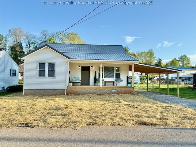 farmhouse inspired home with dirt driveway, an attached carport, metal roof, covered porch, and crawl space