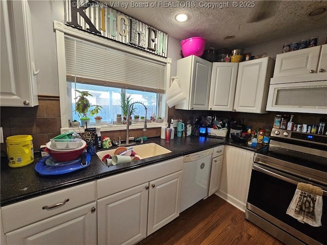 kitchen featuring white cabinetry, white appliances, dark countertops, a textured ceiling, and dark wood finished floors
