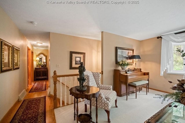 living area featuring baseboards, visible vents, an upstairs landing, and light wood finished floors