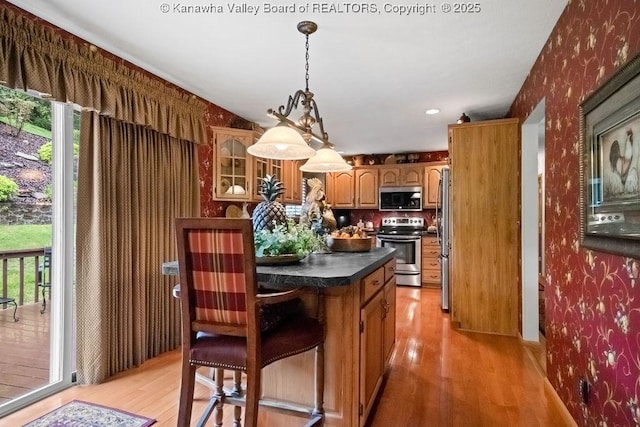 kitchen with glass insert cabinets, wallpapered walls, stainless steel appliances, light wood-style floors, and dark countertops